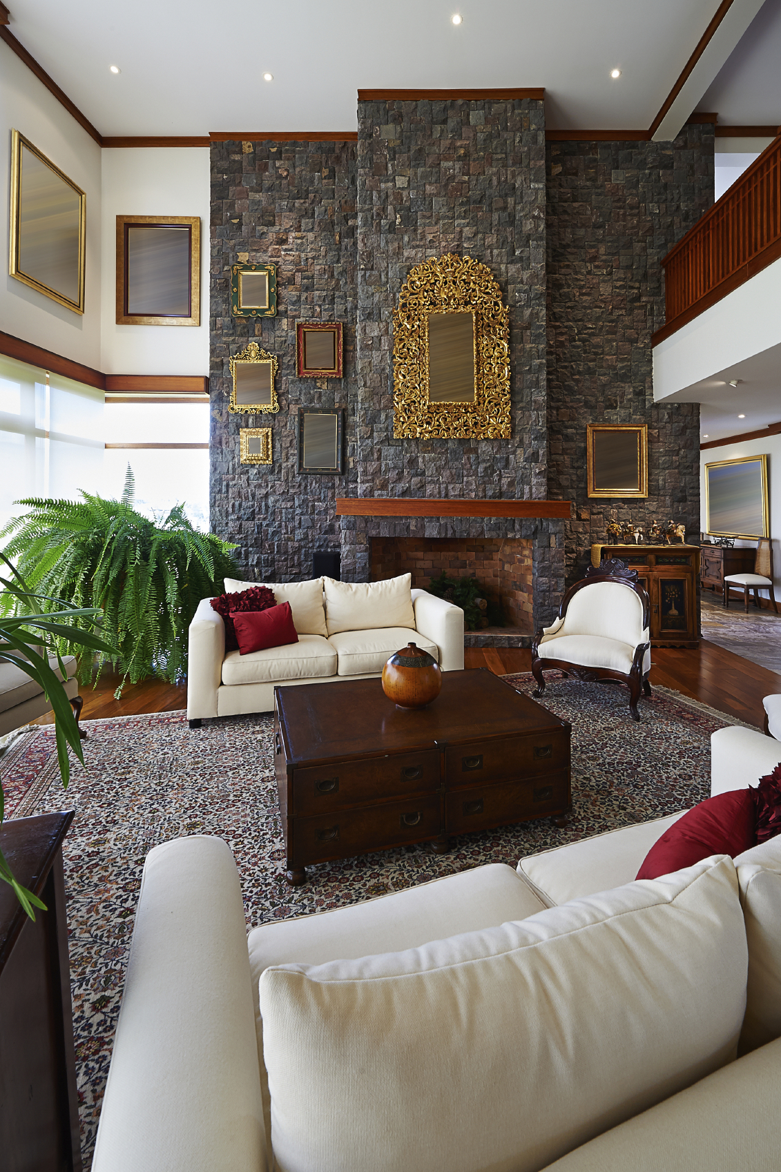 这个豪华的房间以巨大的石砌壁炉墙为主，在铺着大花卉地毯和白色和深色木家具的硬木地板上若隐若现。金色的细节比比皆是，框架画散落在各处。