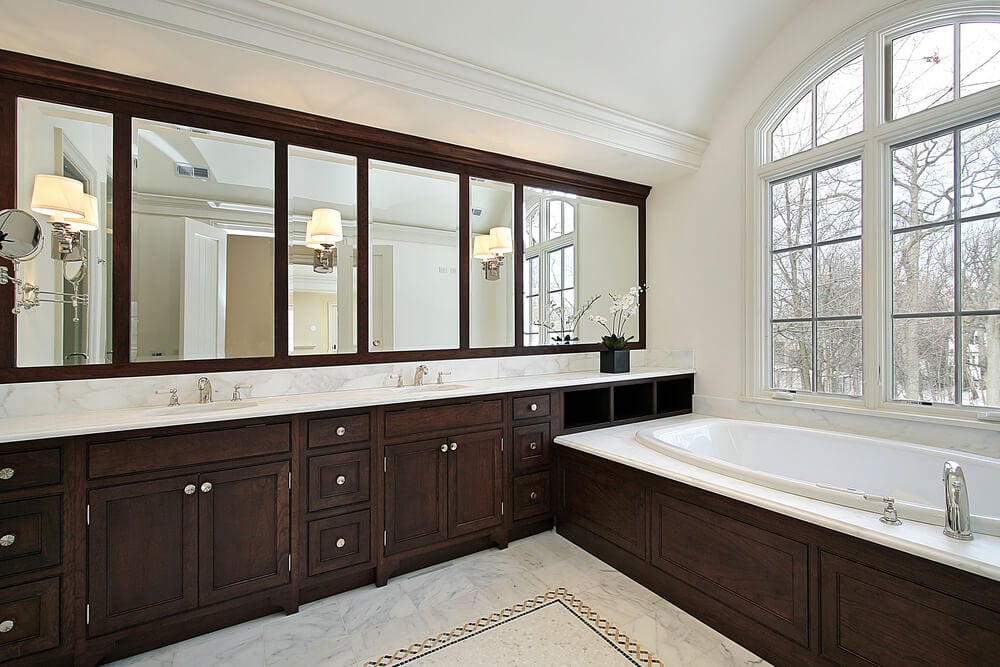 白色浴室与深色木质梳妆台贯穿整个房间，并配有配套的浴室环绕和镜框。大理石地板与台面和浴室周围相匹配。