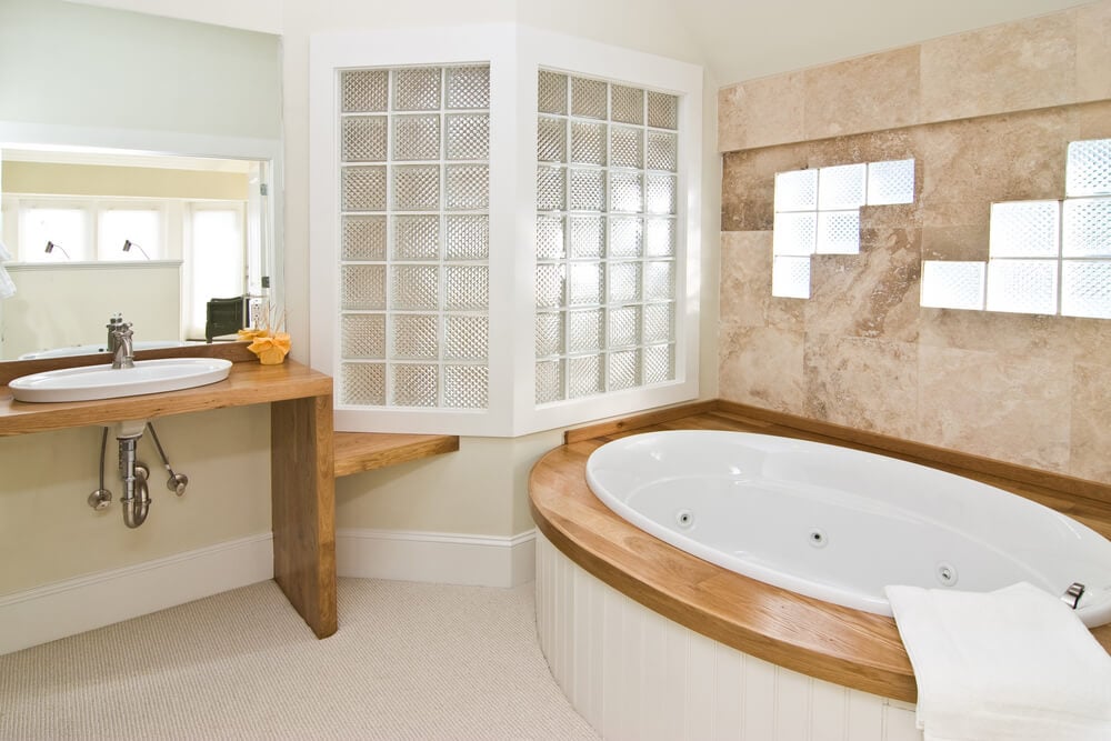 浴室新颖地使用了有纹理的玻璃砖，嵌入瓷砖和白色木材，上面是天然的木质浴架和梳妆台。