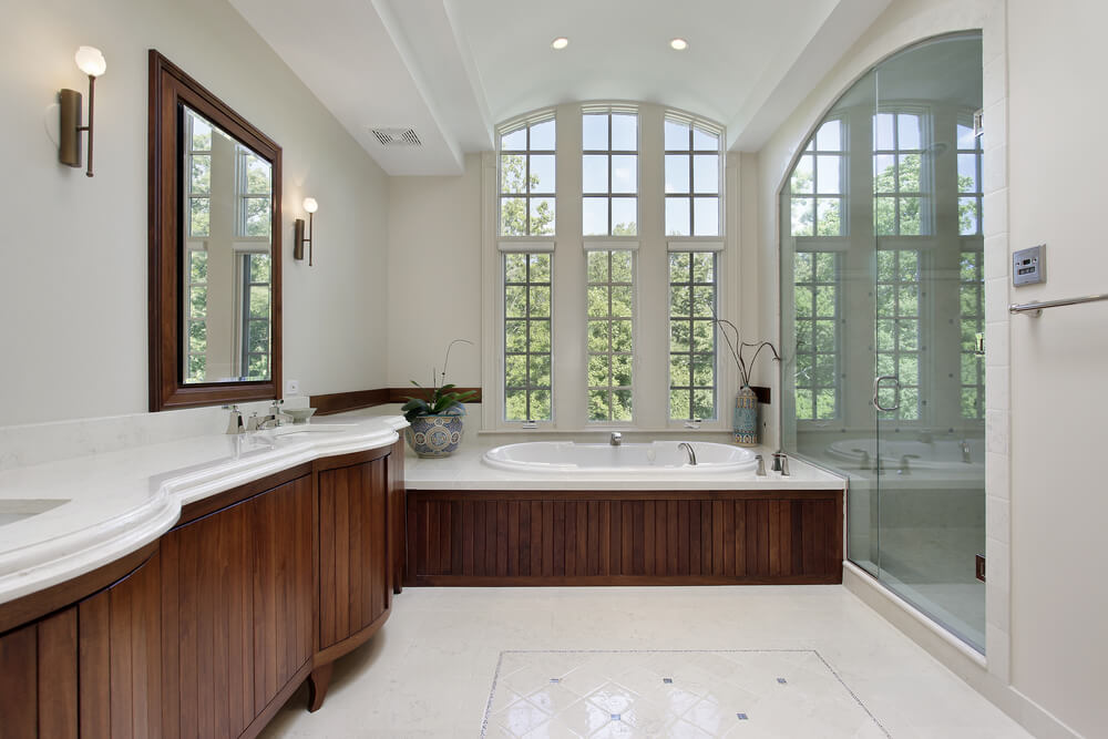 这间白色拱形天花板浴室以丰富的深色木橱柜和浴缸为特色，周围环绕着白色图案<a class=
