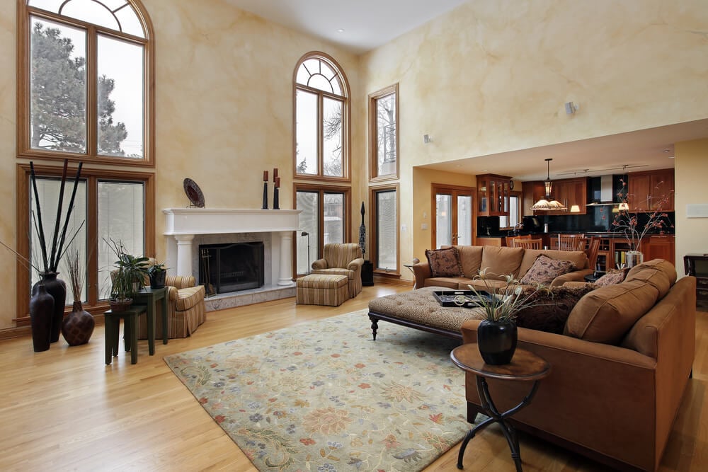 在这个两层楼高的客厅里，大胆的白色大理石壁炉的两侧是落地窗。在一个以浅色硬木地板为主的开放空间里，搭配的棕色沙发围绕着花地毯上的木框架奥斯曼咖啡桌。