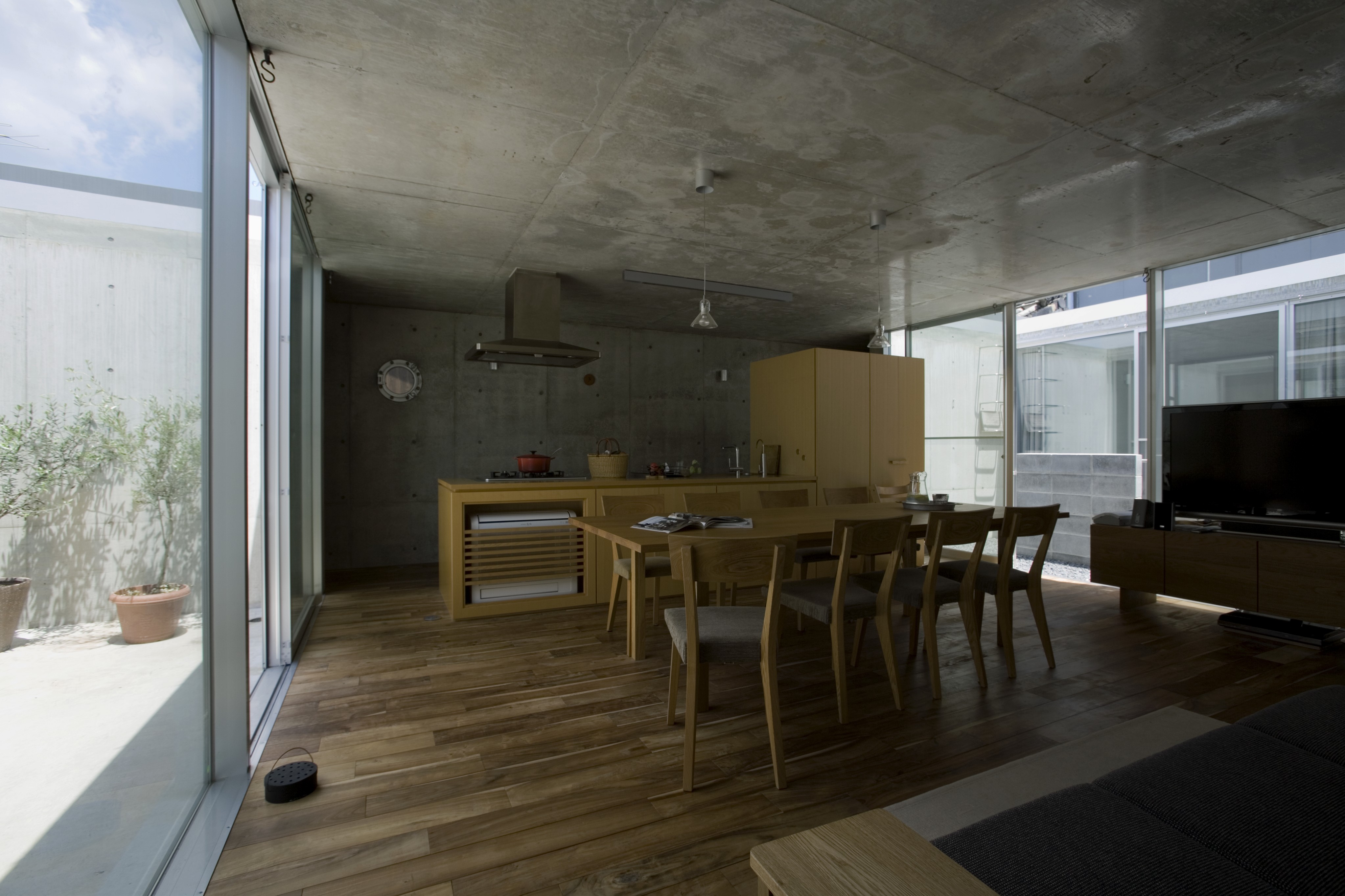 在大的开放式厨房空间中，我们看到浅色的木橱柜和餐桌放置在深色的天然硬木地板上。两端通高的玻璃外墙朝向双露台。