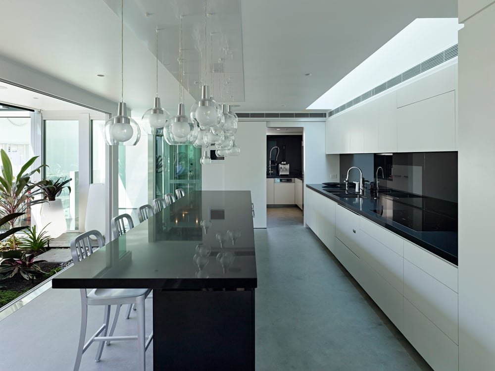 厨房与白色的环境形成鲜明对比，黑色的台面和长长的岛台，上面悬挂着一系列球形玻璃吊灯。