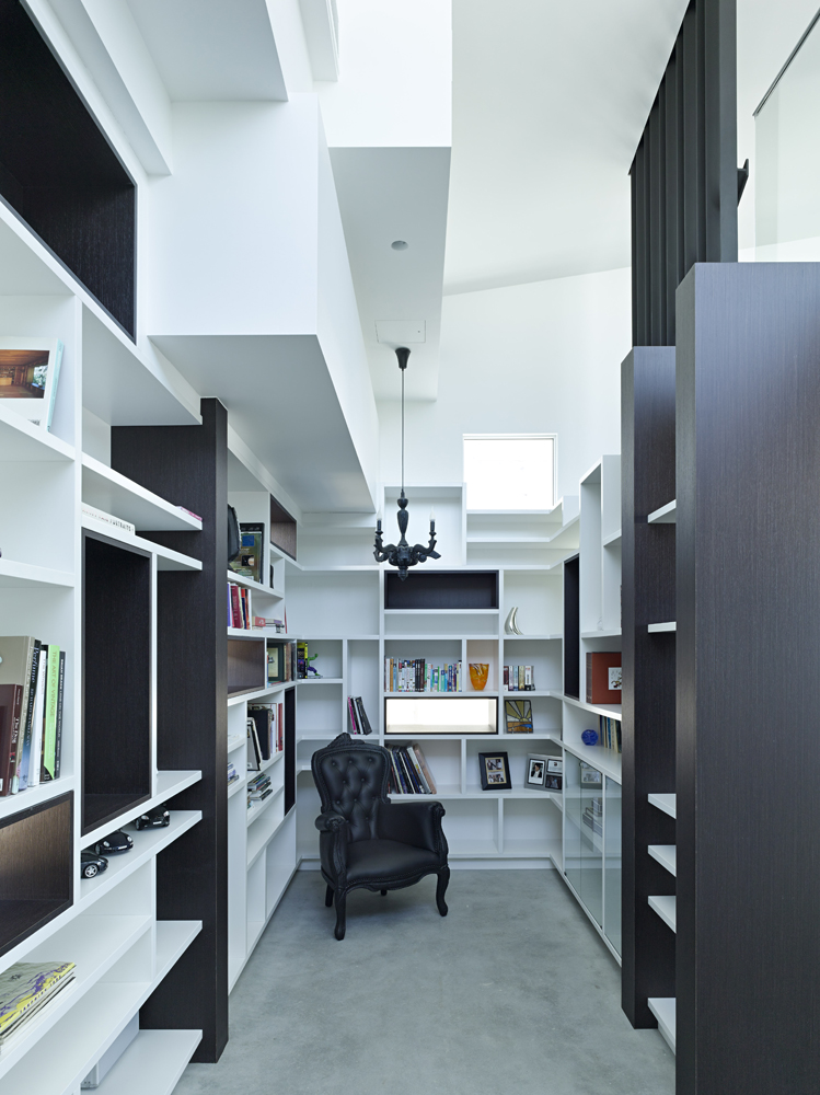 舒适的图书馆空间在每面墙上都有无数的书架选择，深色的木材点缀着白色的装饰。华丽的黑色口音椅子站在中心。