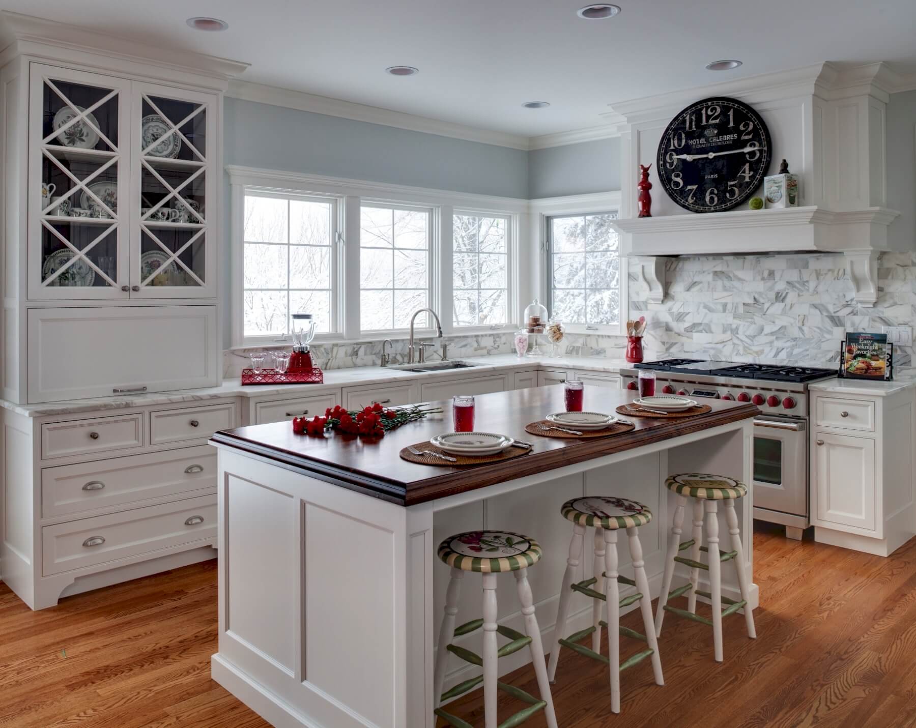 明亮的色调贯穿整个厨房，包括白色橱柜和岛台，温暖的天然硬木地板，以及风格化的大理石瓷砖后挡板。大胆的深色木岛台面与众不同。