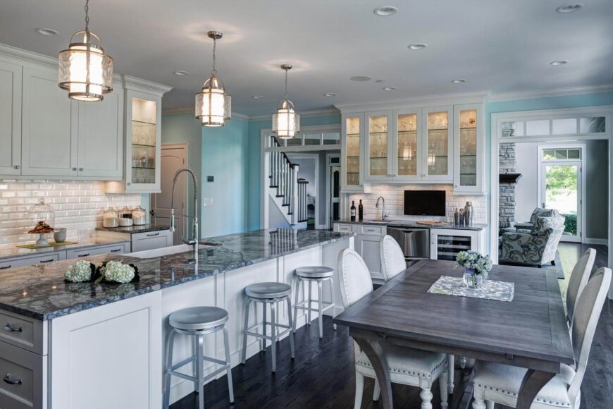 明亮，开放式的设计贯穿整个厨房，站立式白色橱柜和瓷砖后挡板在深色硬木地板上。灰色的餐桌和白色的椅子颠倒了这种对比。