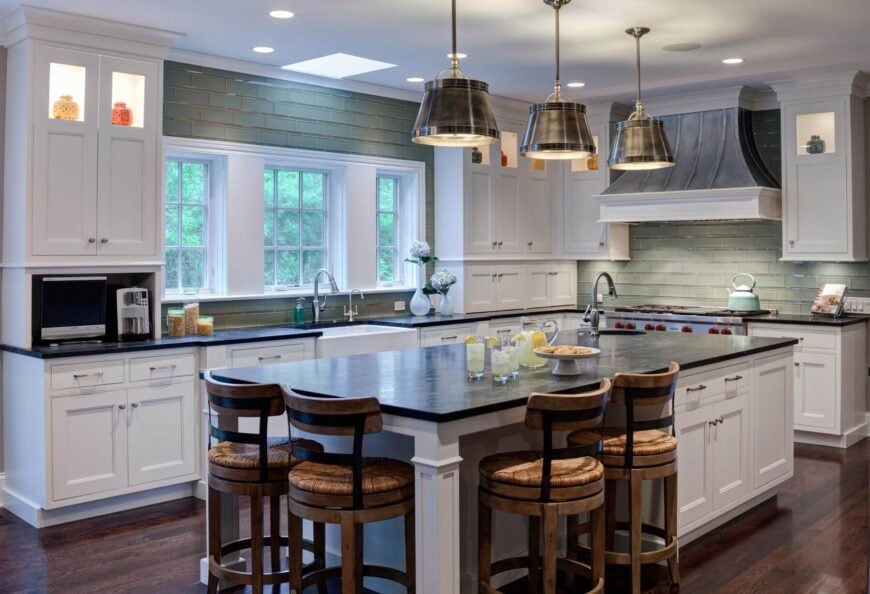 高对比度的现代厨房具有混合色调，包括丰富的深色硬木地板，白色橱柜，绿色瓷砖后挡板和深色台面。
