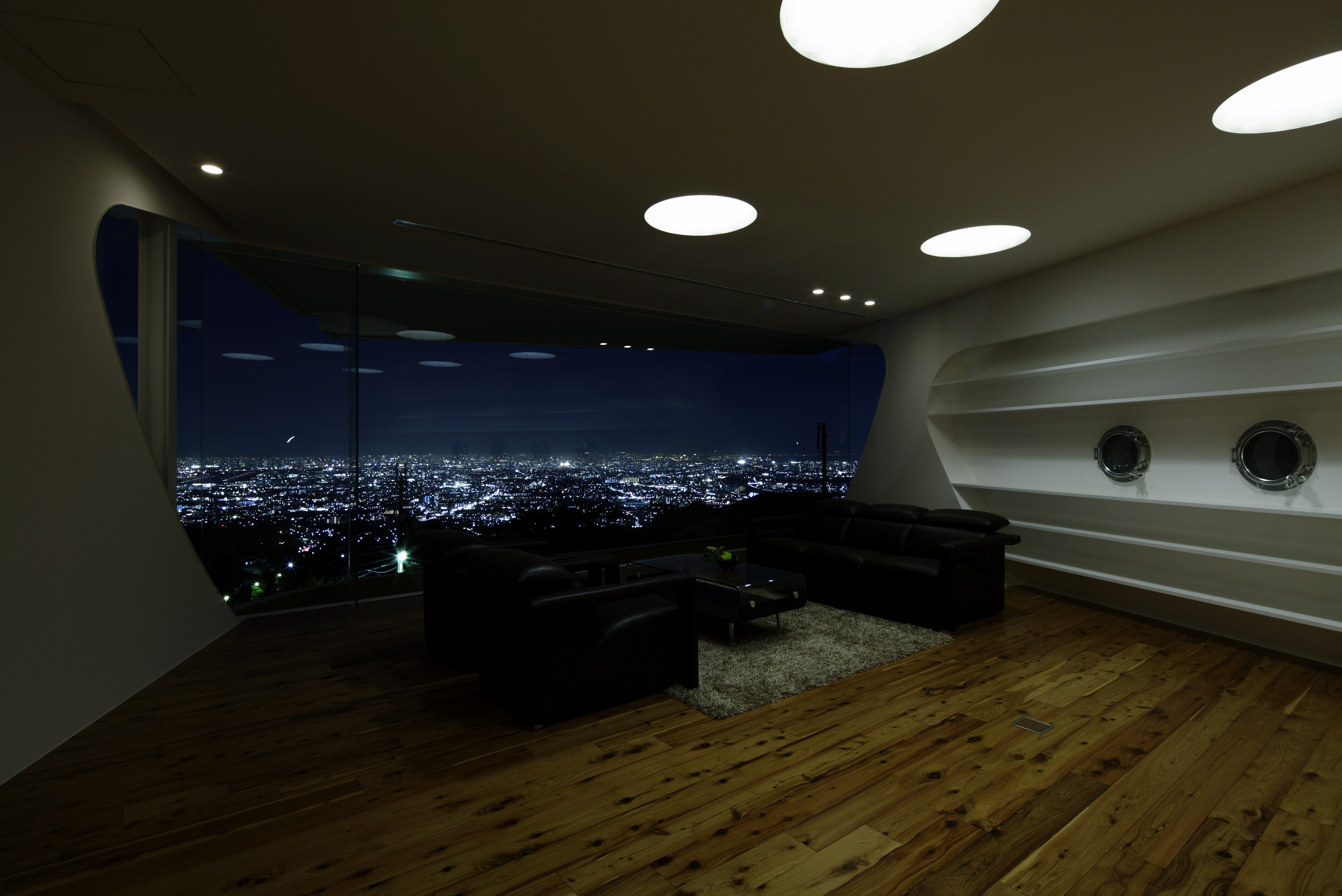 舒适的客厅空间被嵌在天花板洞里的灯巧妙地照亮，右边的架子有航海风格，得益于左孔窗。
