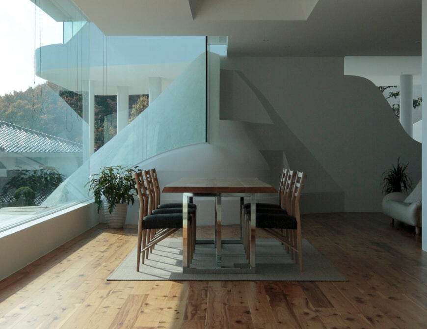 餐桌，在金属框架和雕刻木表面，站在巨大的地板到天花板的玻璃旁边，俯瞰壮观的景色从这个家庭的较低水平。