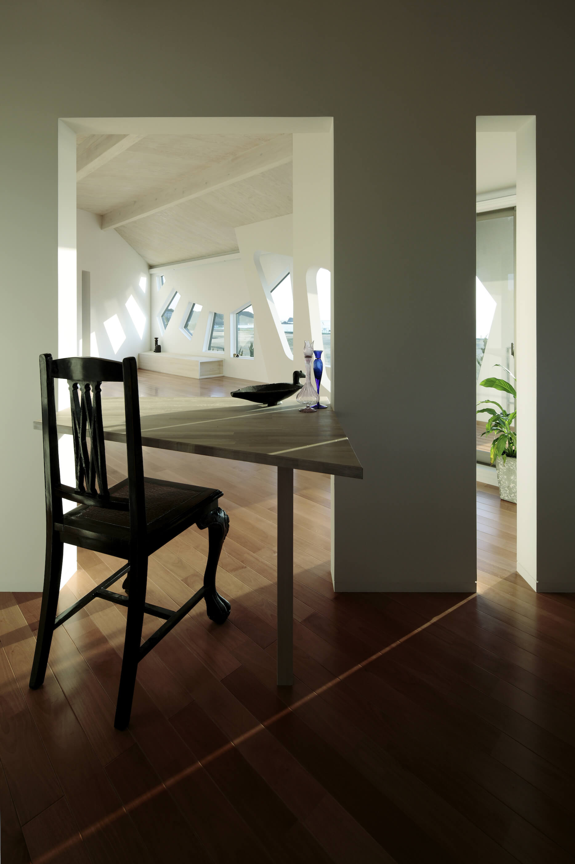 角和有机形式混合在整个家庭。这张天然木桌反映了多边形的窗户形状，通过墙缝可以看到开放的客厅空间。