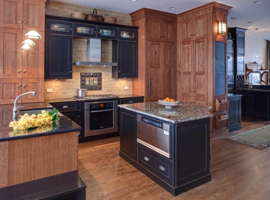 郁郁葱葱的天然硬木地板和全高橱柜环绕黑色染色橱柜和岛在这个开放式厨房。复杂的瓷砖后挡板和照明选项添加独特的亮点。