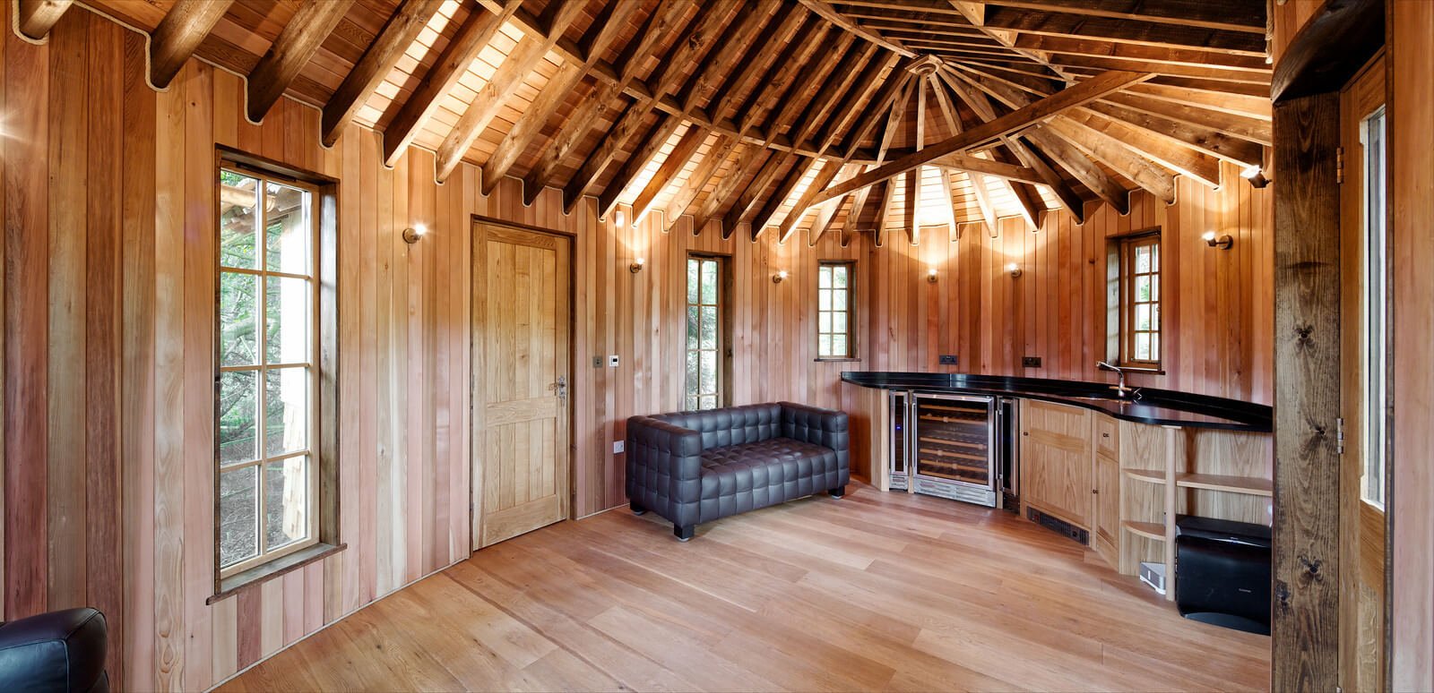 建筑的一侧是现代化的小厨房，光滑的黑色台面和周围的天然木材。玻璃窗户让自然光进来，但有壁灯作为补充。