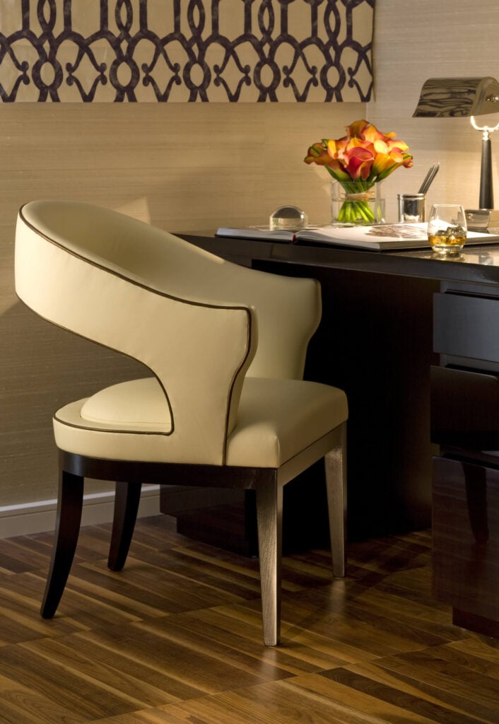 一个小的角落办公空间由这张丰富的深色木桌和当代奶油色皮革椅子组成。