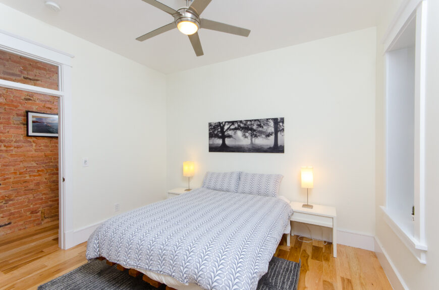 第二间卧室采用了极简主义设计，配有光滑的白色床头柜。全白的房间使蓝色的床上用品和地毯成为房间的焦点。