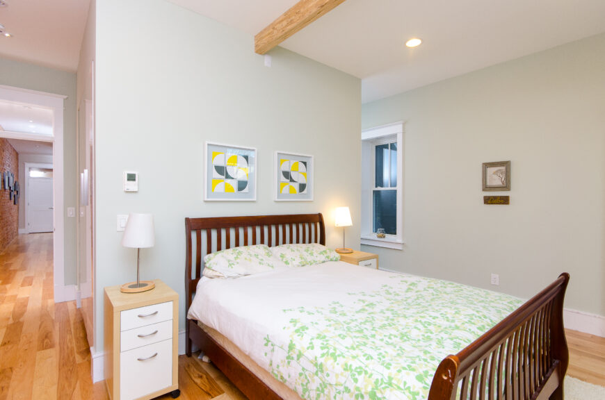 从卧室的另一个角度看，通向左边的长长的走廊和浅色松木硬木地板。