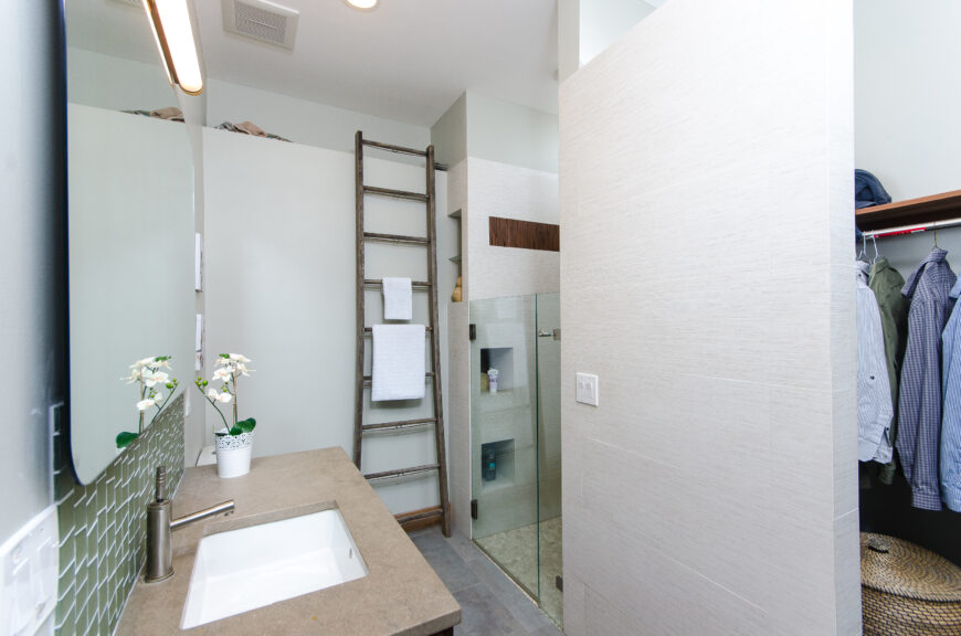 一扇较短的玻璃门包围着白色瓷砖淋浴间和内置的小隔间。拐角处有个步入式衣帽间。