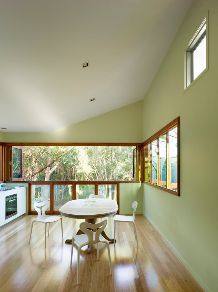 上层的用餐空间设有一组可伸缩的百叶窗，允许该区域自由开放。天然硬木地板与浅色墙壁形成对比。