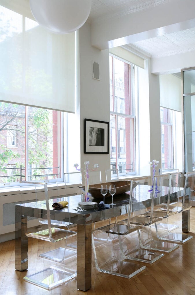 高耸的开放空间与超现代的餐厅共享，由镜面餐桌和一组丙烯酸椅子组成，形成水晶般的外观。巨大的通高窗户自然地照亮了空间。