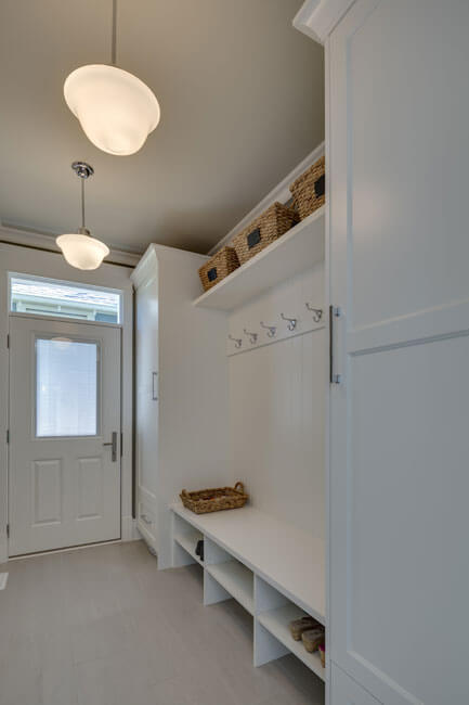 一个全白色的储藏室，有很多存储选择;储物柜，挂钩，和上面和下面的板凳架。