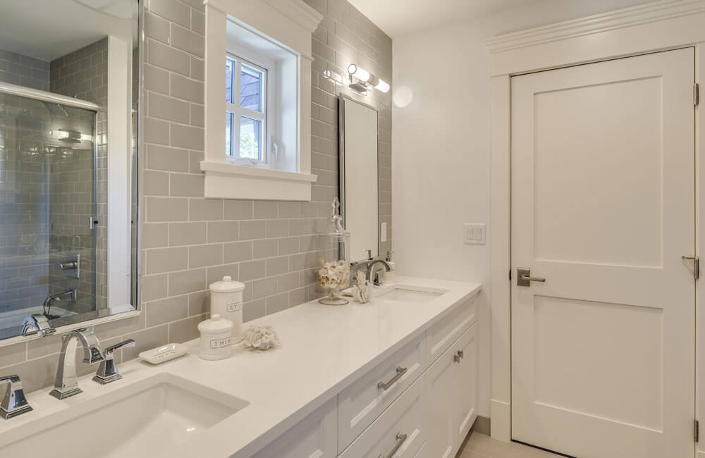 客用浴室以白色为主，设有男女盥洗池。灰色瓷砖后挡板延伸到淋浴和浴缸外壳。