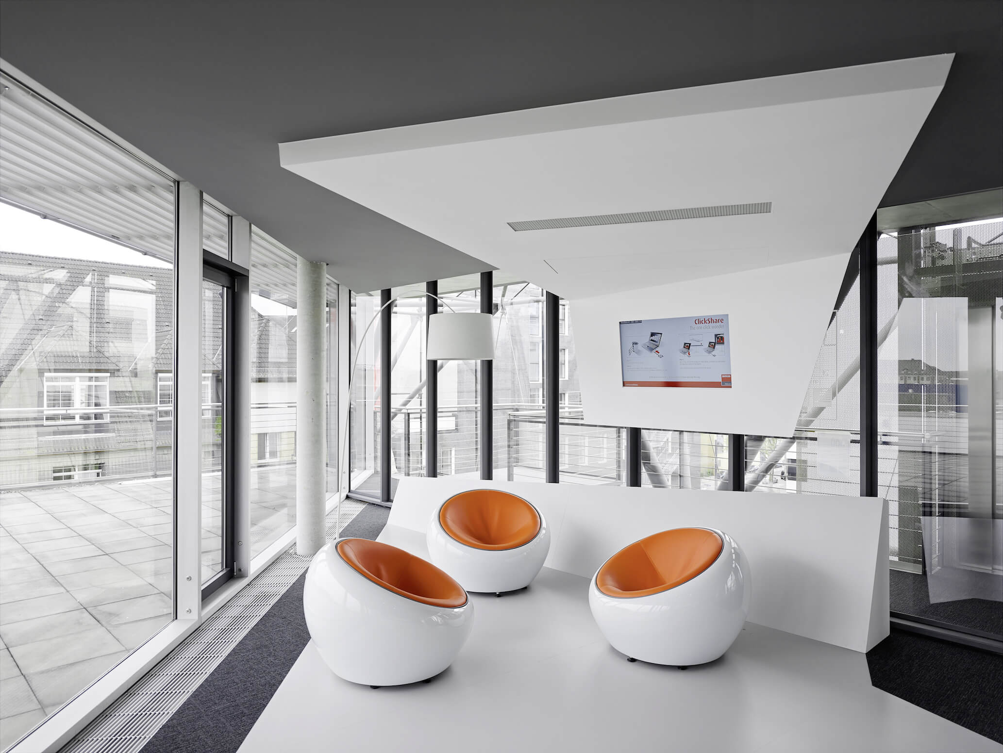 在这里，我们可以更仔细地观察这三张橙色皮革座椅的“鸡蛋”椅。全高玻璃环绕着空间，提供自然光线和广阔的极简主义感觉。
