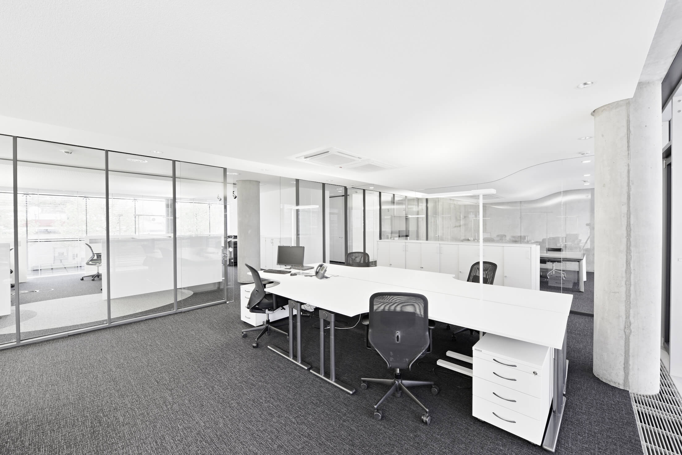 扫视一排由落地玻璃隔开的办公空间，人们可以欣赏到这种设计的开放性，使离散的空间有一种连续性。光滑的白色和金属桌子强调了亮度。