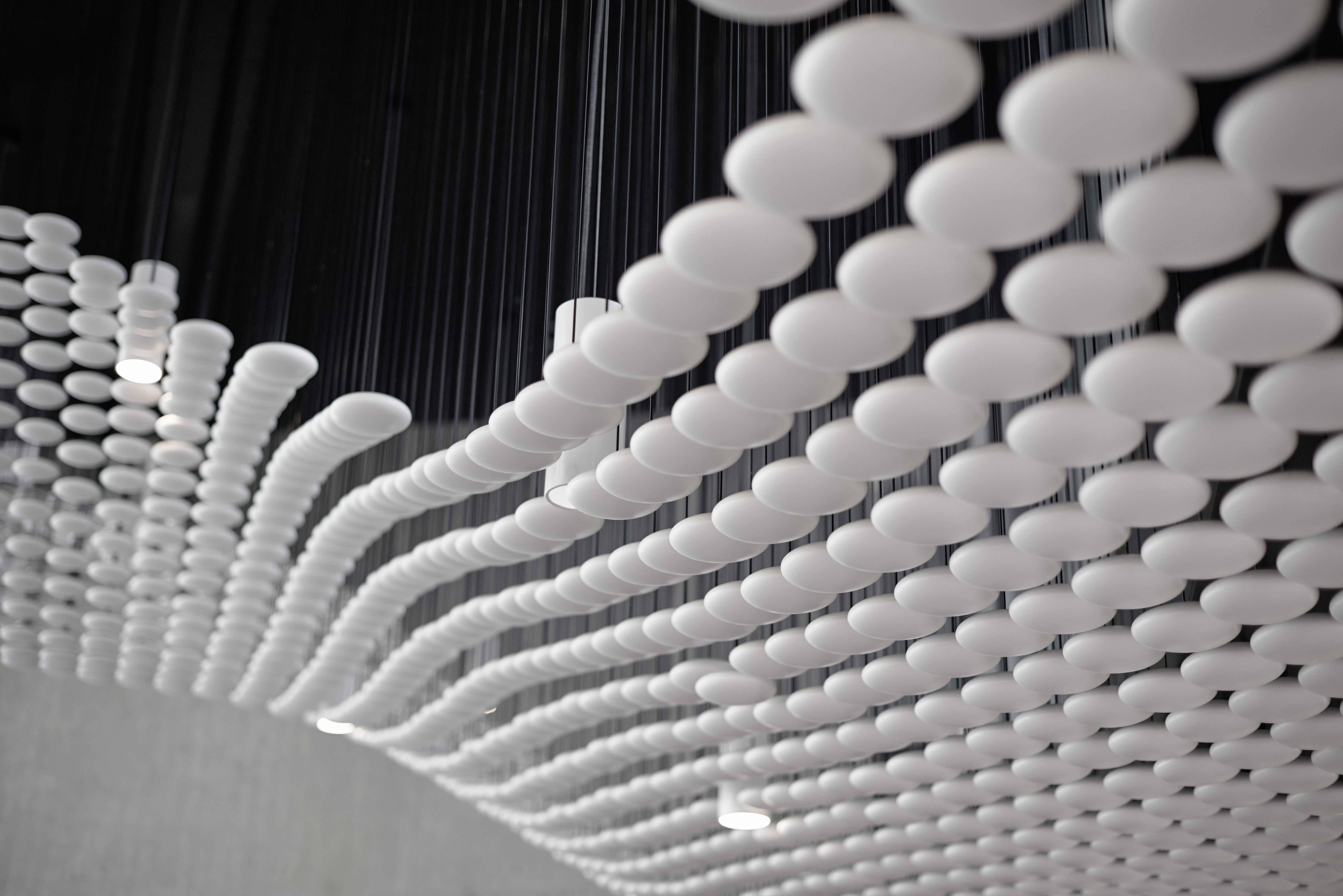 白色球体漂浮在入口通道上，每个球体都悬挂在天花板上的一根电缆上。