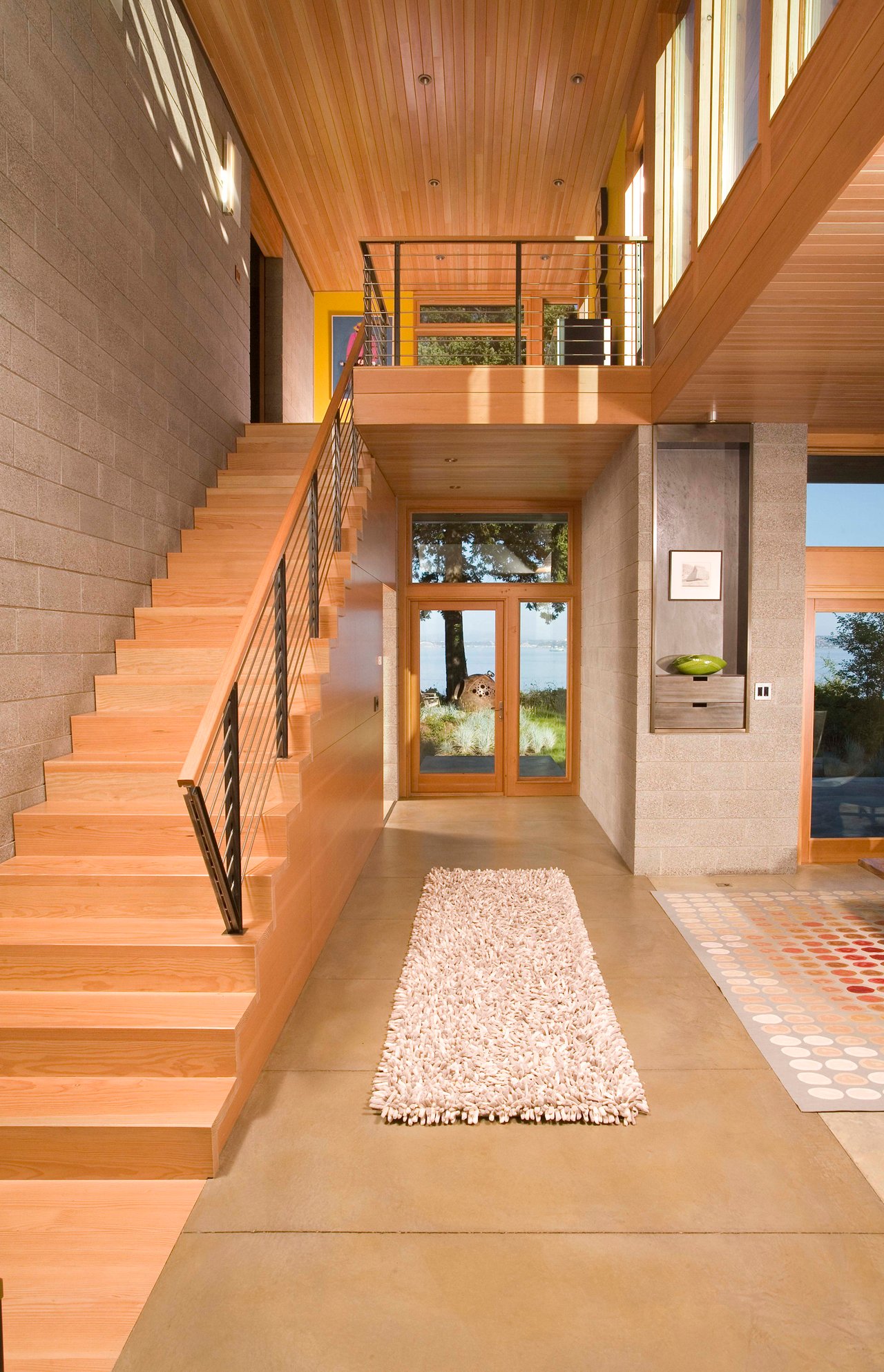 这个可爱、温暖的入口右侧有一个主要的起居区，左侧有一个楼梯，前方的短走廊通往后院。入口是温暖的木材和中性的石材瓷砖的组合。