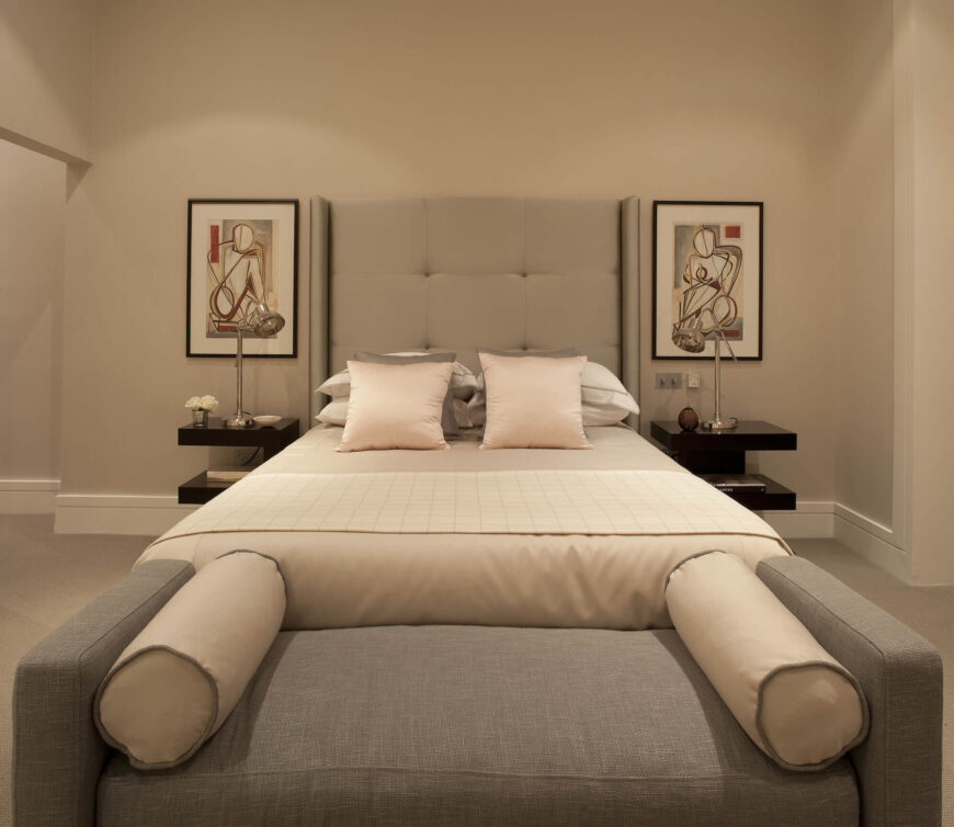 第二间卧室里也有类似的床和长凳，这次是更明亮、柔和的色调。一个巨大的纽扣簇绒床头板位于一对印象派画作之间，两侧是两层的床头架子。