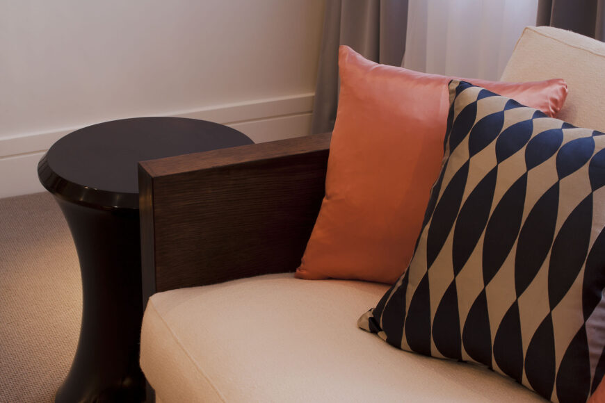 沙发的近景突出了丰富的木材色调和图案和彩色枕头的对比，米色的缓冲垫与地毯相匹配。