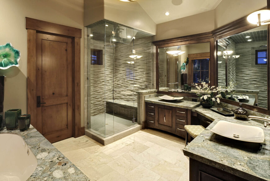 豪华的主浴室设有环绕式双梳妆台，大理石台面和深色木橱柜上有容器水槽。大画幅镜子和封闭的玻璃淋浴间增添了明亮和开放的感觉。