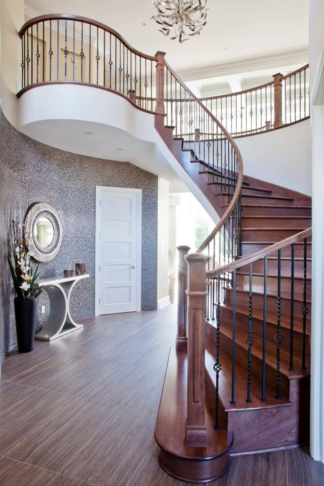 这个当代风格的门厅有独特的木纹地板，抛光的樱桃木楼梯踏板，以及大胆的图案墙处理。一个大的圆形平台可以从二楼俯瞰门厅。