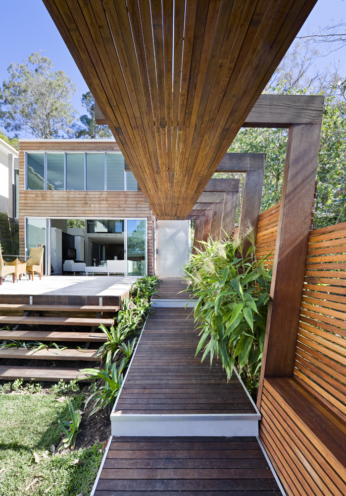 深色的木露台沿着院子的长度层层延续，与右边的大横梁和较小的木条搭配，形成现代风格而又自然的外观。