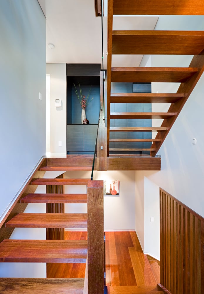 开放式设计的天然木楼梯以玻璃栏杆为特色，强调视觉的透明度。上层突出使用了深色染色木橱柜和墙板，与白色环境形成对比。