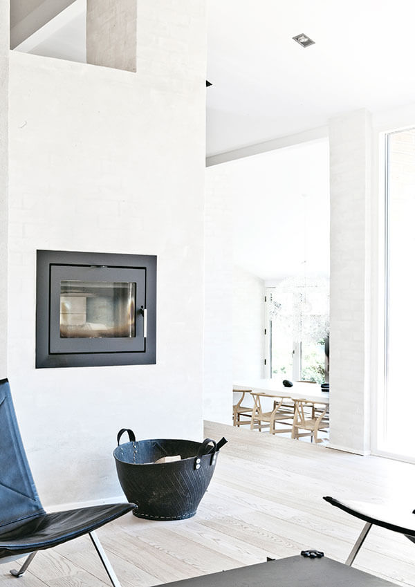 独特而微妙的壁炉以黑色为框架，形成最大的对比，与明亮空间中的深色家具色调相融合。从这里，我们可以看到房子对面的角落。