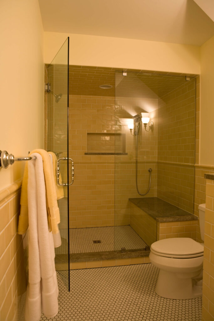 大型步入式淋浴间是全玻璃封闭的，白色微瓷砖地板上铺满了柔软的米黄色瓷砖。