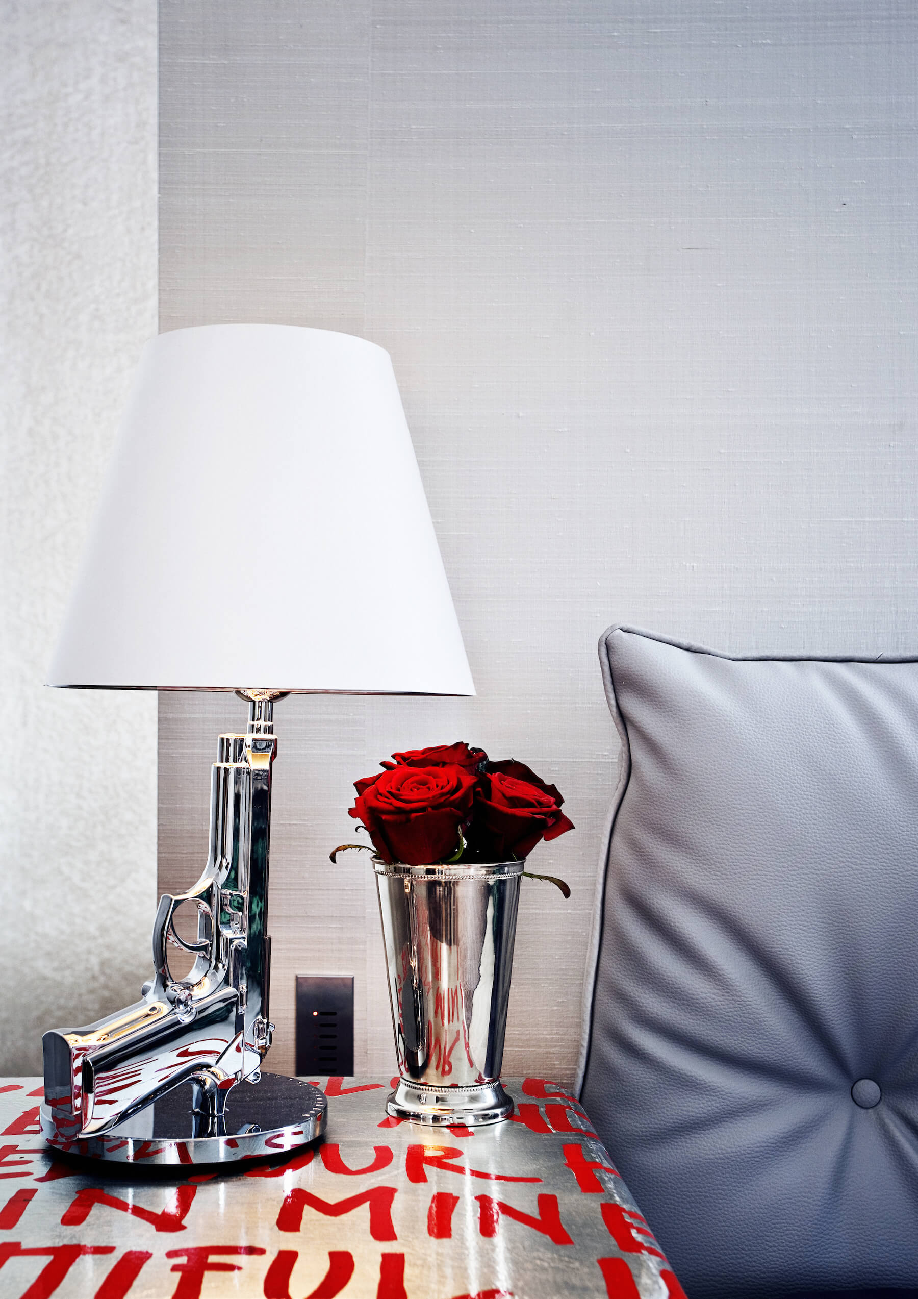 银色调床边梳妆台与红色文字绘画持有一个镀铬花瓶和这引人注目的手枪设计灯。