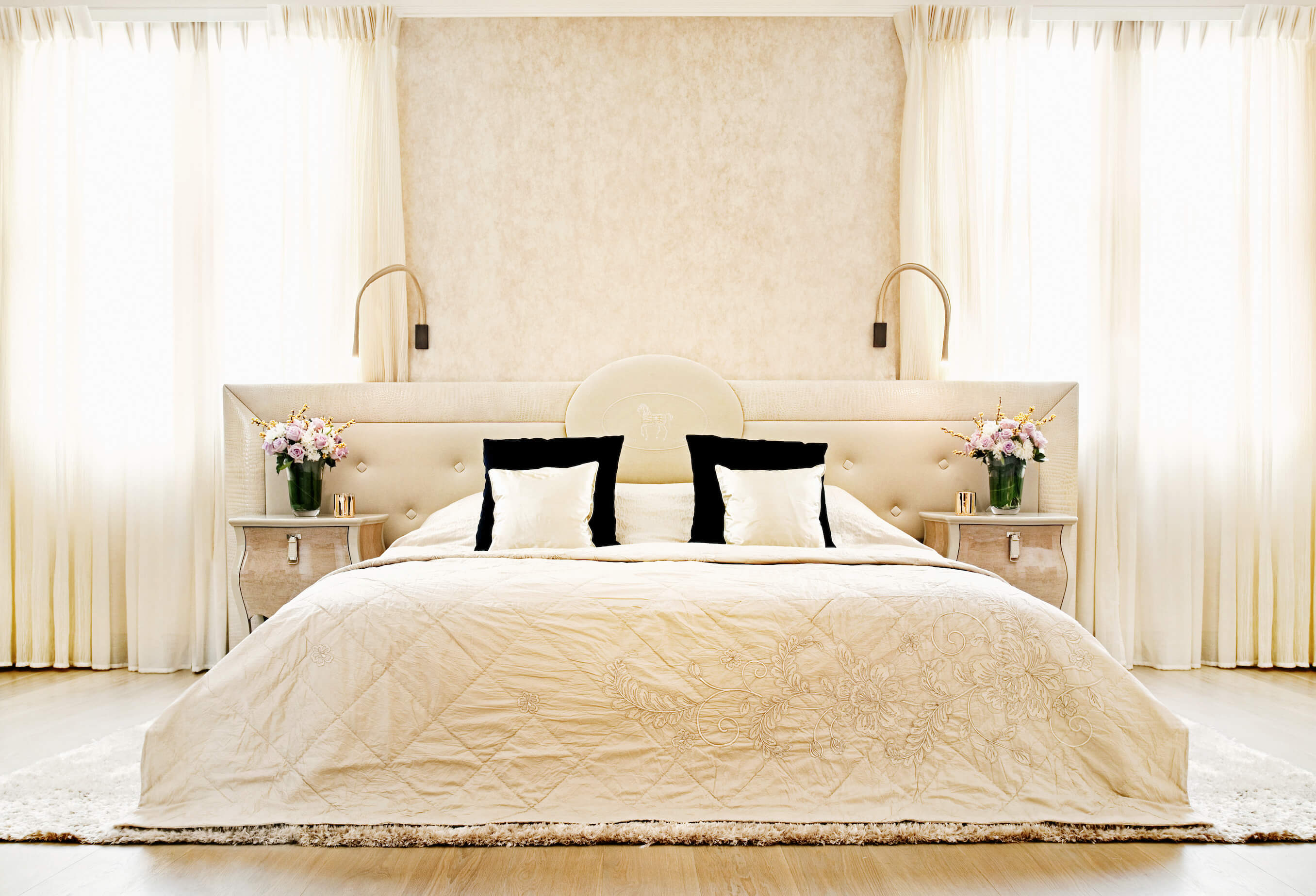 主卧套间充斥着大胆的奶油色调，从窗帘到大的纽扣簇绒床头板，两侧是一对雕花木梳妆台。另一块厚厚的地毯将房间里的家具固定在硬木地板上。