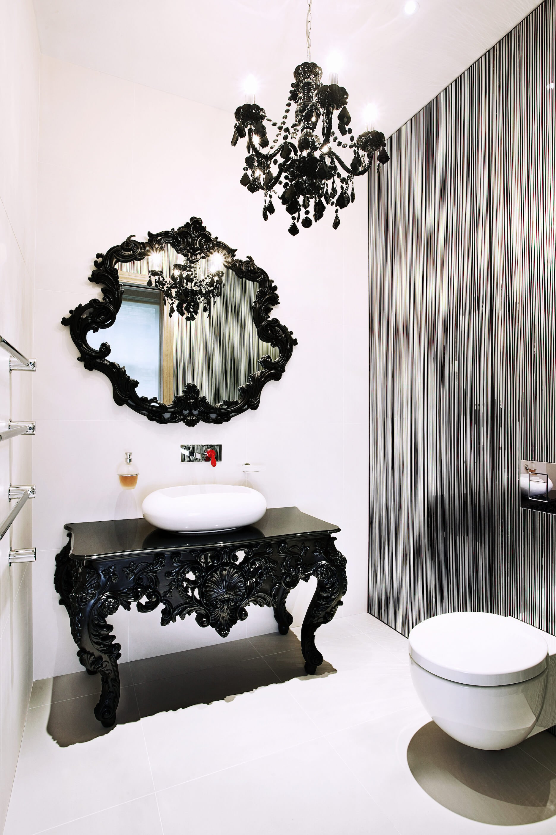 最后，我们有另一个完全不同的浴室。这个例子是一个华丽的，传统风格的黑色梳妆台和白色的容器水槽，下面是一个互补的黑色镜框镜子。银色竖条纹墙与白色瓷砖形成鲜明对比。