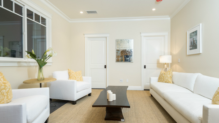 休闲的客厅里有可爱的白色当代家具，淡黄色的枕头与天然纤维地毯相得益彰。深色天然木茶几造型独特。