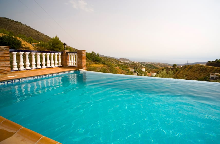 这座托斯卡纳风格的露台在山边有一个深蓝色的无边泳池，可以欣赏到古雅的乡村和远处的水。