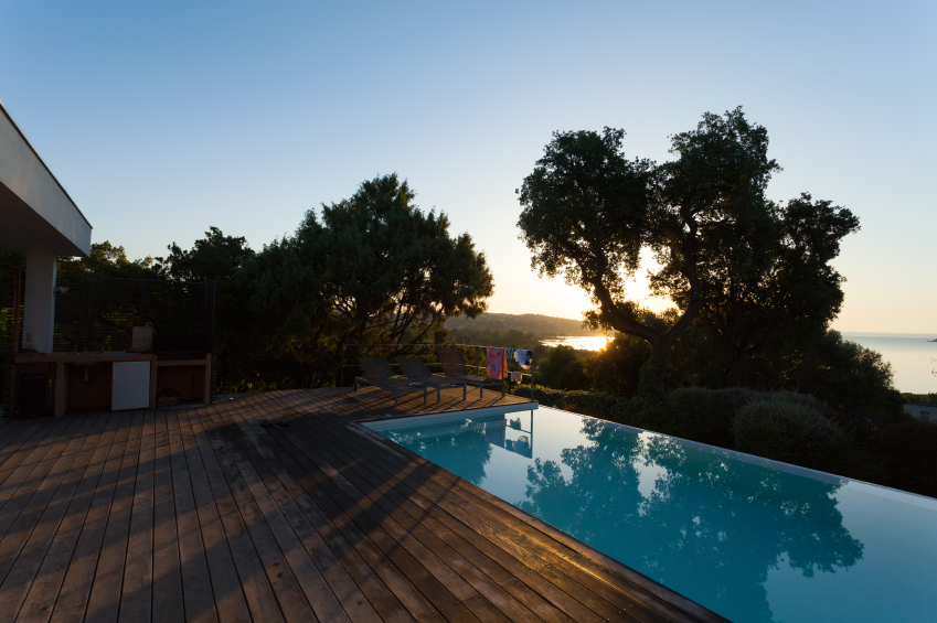 简单的木甲板围绕着这个游泳池的三面保持对游泳池和可爱的日落的关注。