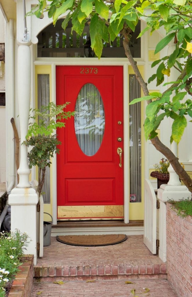 这座房子的前门有一条古老的砖砌走道，上面有一个白色的小门，为亮红色的金色装饰门增添了农舍的魅力。
