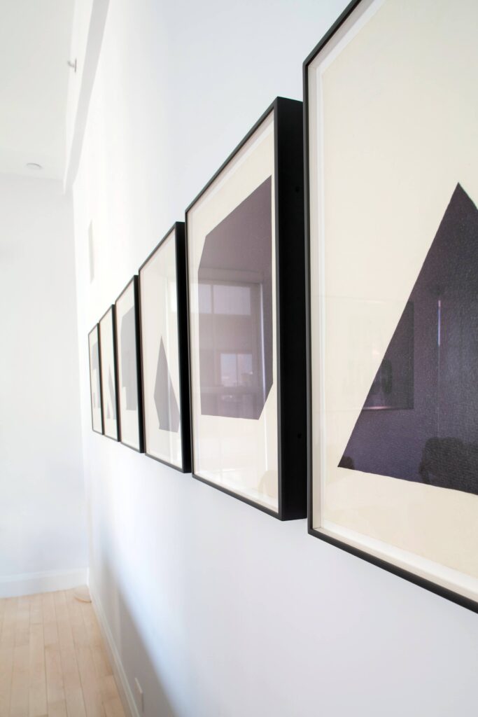 客厅墙上的一系列极简主义作品以深色木材为框架，为白色空间增添了细节和对比。
