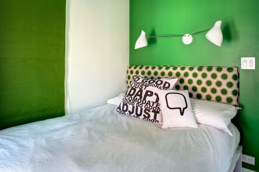 第二个儿童房的白色被褥上有大胆的绿色墙壁，而床头板上的圆点图案则是绿色的。