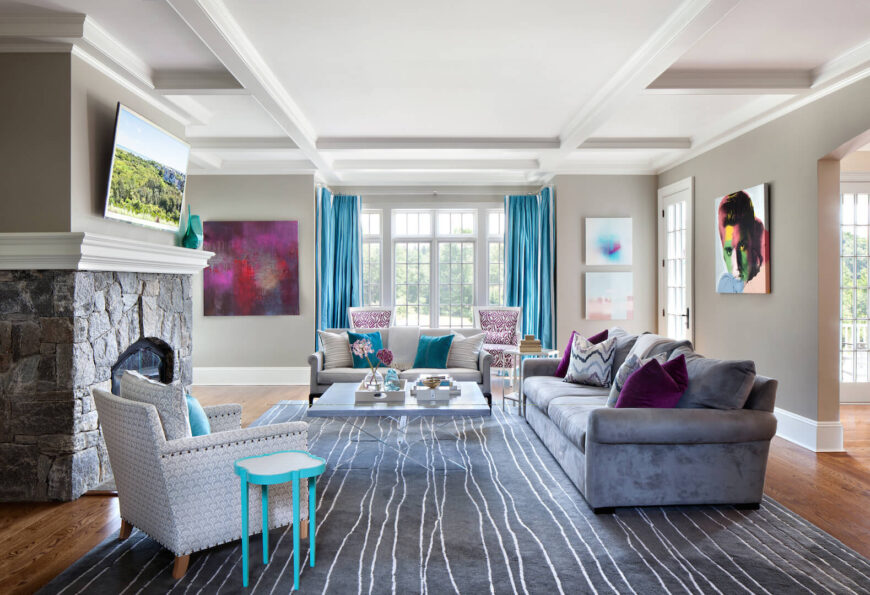 客厅的特色是有图案的椅子和暗紫色天鹅绒沙发。灰色石砌壁炉上方是一台壁挂式电视。房间里的艺术品包括明亮的现代绘画和对猫王的现代诠释。绿松石色和浆果色为这个房间增添了大胆的色彩。