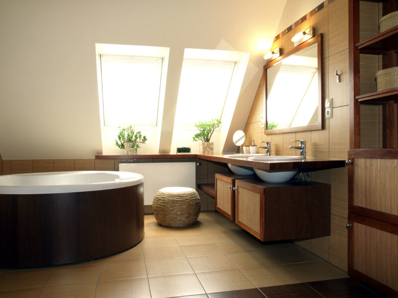 一间极简主义风格的浴室，梳妆台台面上方有两扇天窗。两个容器水槽位于开放式搁板和橱柜上方。这间浴室充满了天然纤维和石头，营造出一种非常禅意的氛围。