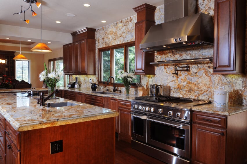 一个豪华的深色木材厨房，有大量的大理石后挡板与橙色纹理。