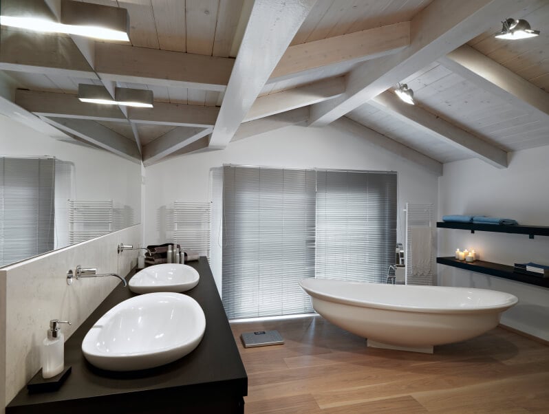 一间时尚简约的阁楼浴室，配有开放式搁架和船状水槽，与独立式深蹲浴缸相匹配。光滑的墙壁安装装置完成外观。