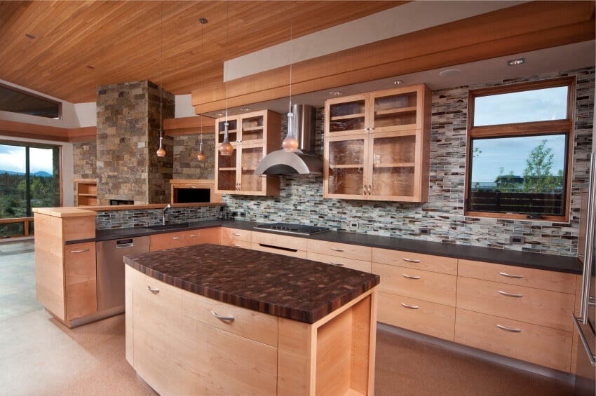 现代风格的轻木厨房，带有后挡板，一直延伸到壁柜上方的悬垂部分，那里有嵌入式照明。